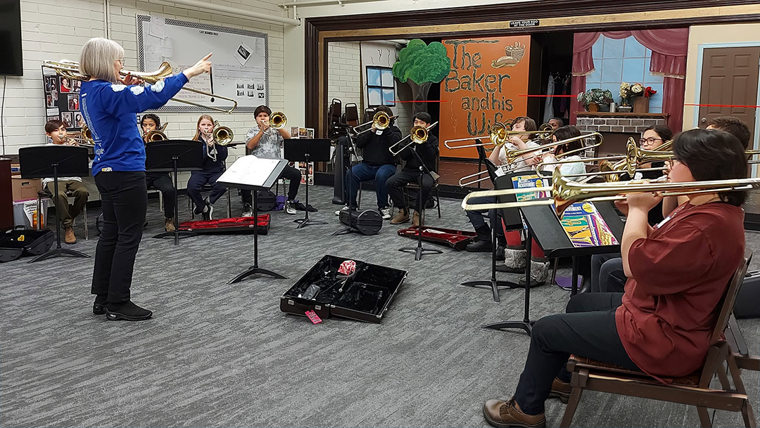 Music instructor leading young trombone players during a KAFY band rehearsal.
